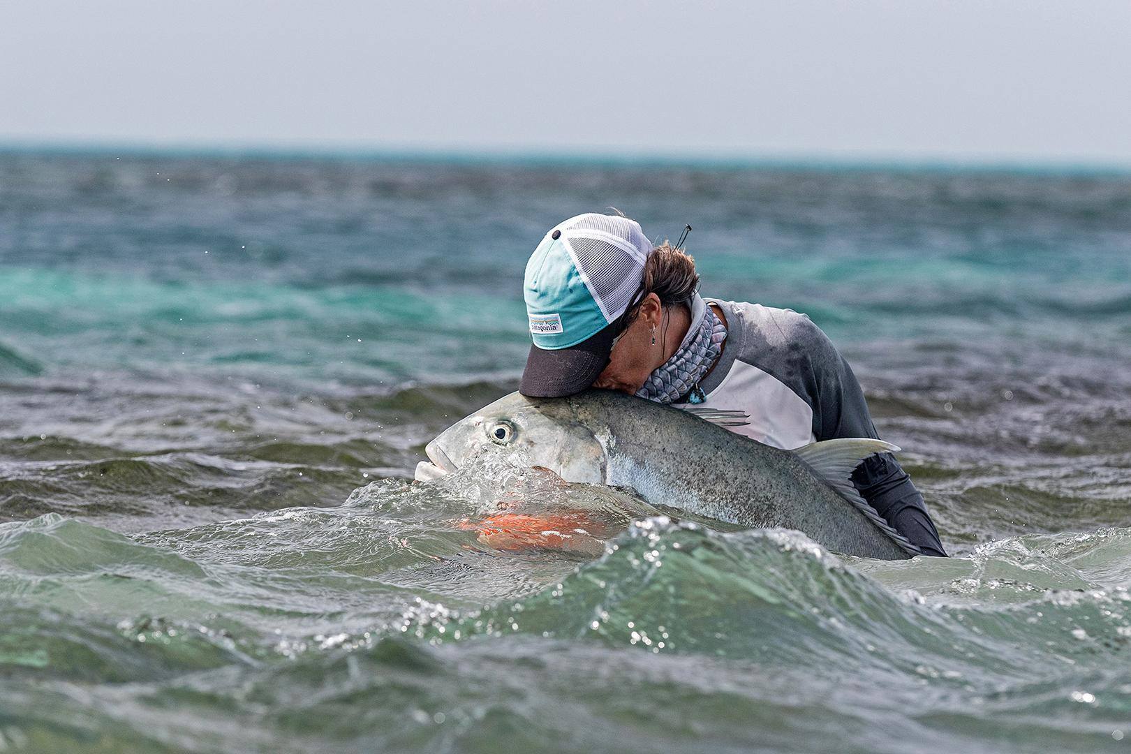Millie Paini shares a tender moment with her fifth Giant Trevally of the day in the Seychelles.