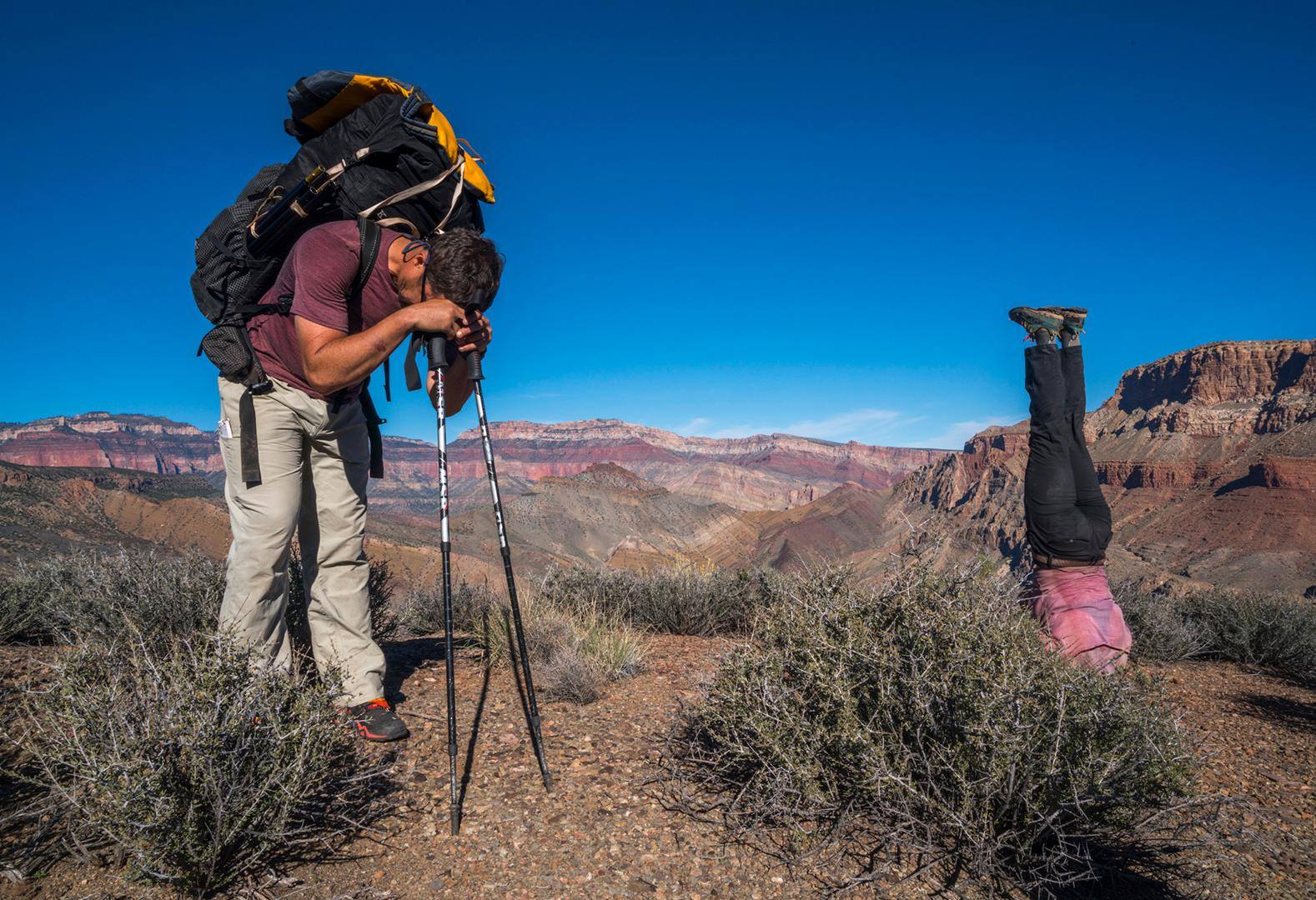 Same experience, different perspectives: Kevin Fedarko rests on his poles, while Kelly McGrath stands on her head, subsequent to a five-hour climb to the rim of the Grand Canyon after hiking its 750-mile length.
