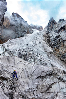 Whitney ropes up on rugged and steep terrain during the approach to an unclimbed peak in the Kishtwar Himalaya, India.